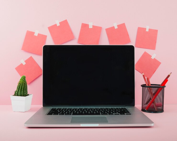 Foto gratuito ordenador portátil con pantalla negra en blanco en el escritorio de oficina rosa