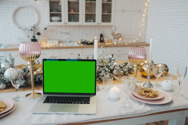 Ordenador portátil con pantalla verde - chromakey cerca de las decoraciones de año nuevo. tema navideño. modelo.