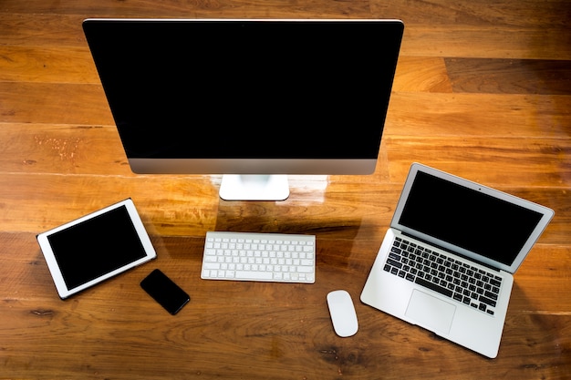 Ordenador, portátil y tablet vista desde arriba en una mesa de madera