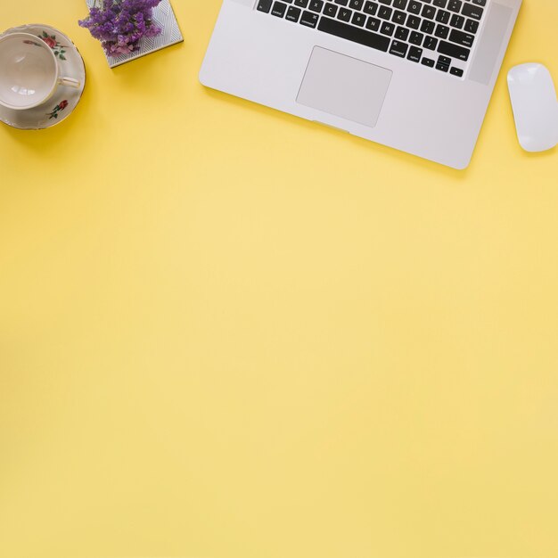 Ordenador portátil y taza vacía sobre fondo amarillo