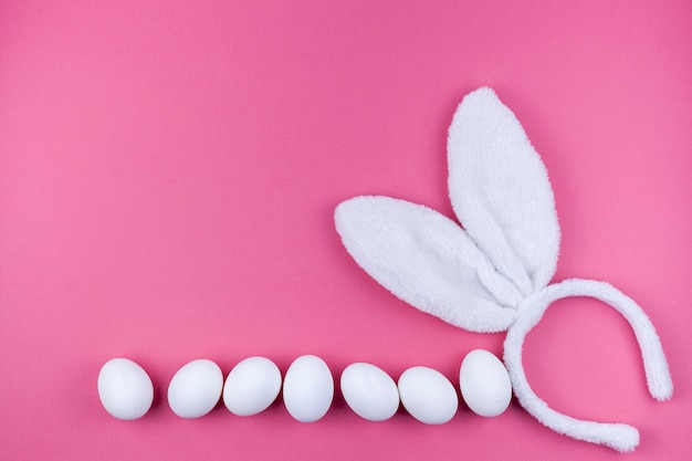 Orejas de conejo con huevos blancos sobre fondo rosa