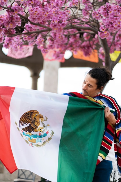 Foto gratuita orgulloso joven sosteniendo la bandera mexicana tiro medio