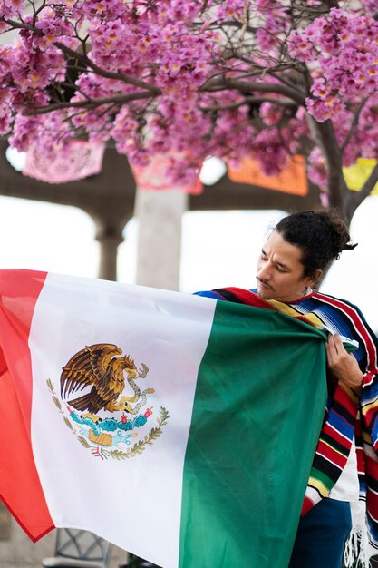 Orgulloso joven sosteniendo la bandera mexicana tiro medio