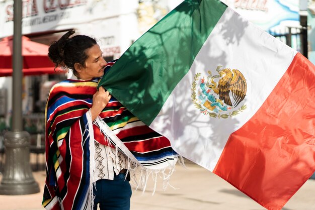 Orgulloso joven sosteniendo la vista lateral de la bandera mexicana