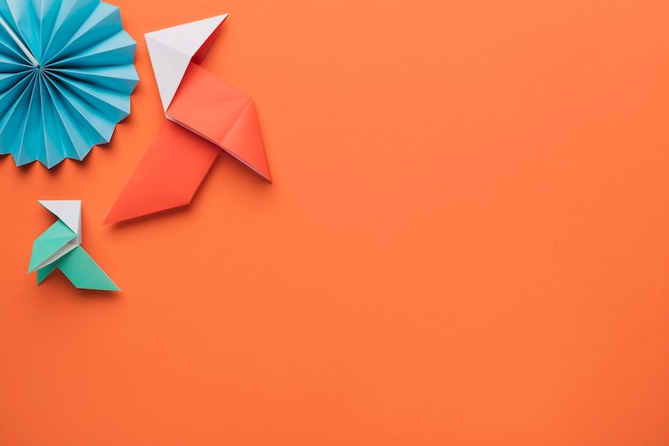 Foto gratuito origami arte de papel artesanal en superficie naranja oscuro