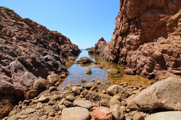 Orilla del mar rodeada de rocas y el mar bajo la luz del sol