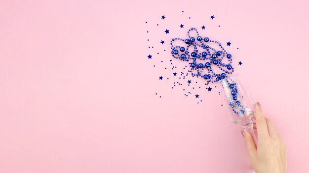 Oropel azul en un vaso sobre fondo rosa copia espacio y mano