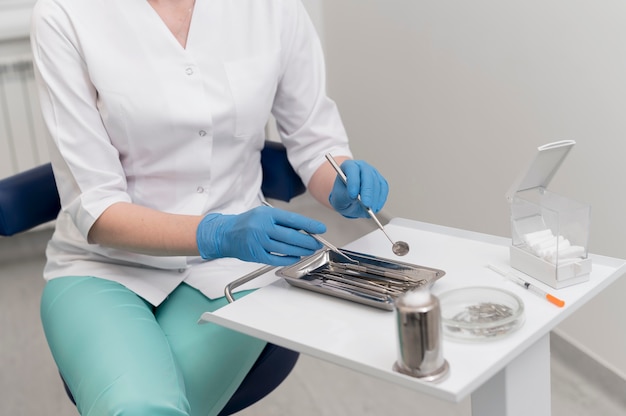 Foto gratuita ortodoncista femenina con guantes de látex manipulando equipos dentales