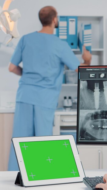 Ortodoncista con pantalla verde horizontal en tableta para cuidado bucal y odontología. Mujer que trabaja como dentista con clave de croma y plantilla de maqueta aislada mientras mira escaneo de dientes