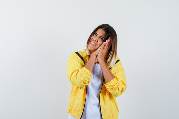 Ortrait de dama apoyada en las palmas como almohada en camiseta, chaqueta y mirando feliz vista frontal