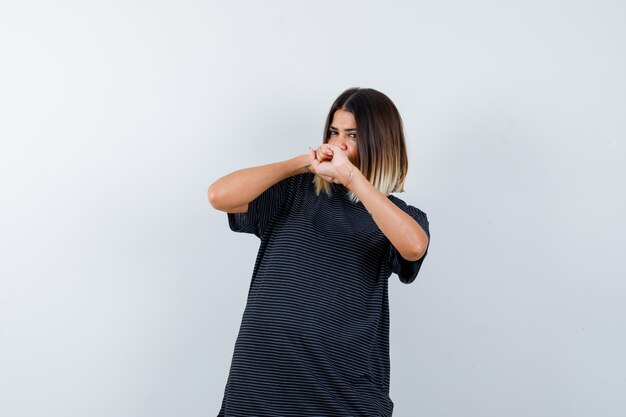 Ortrait de dama posando con puños levantados en camiseta negra y mirando confiada vista frontal