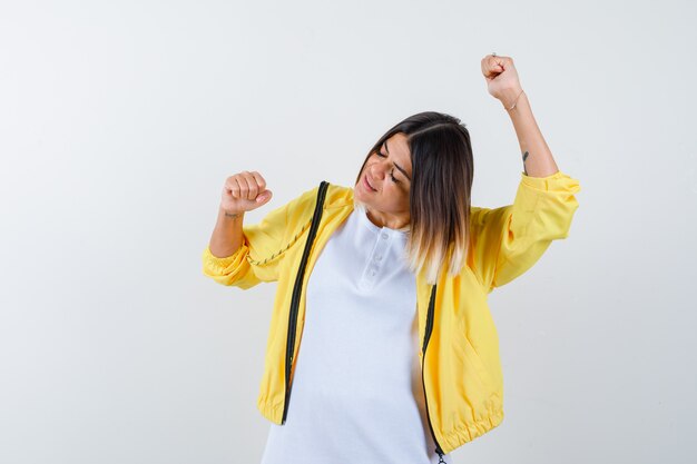 Ortrait de mujer mostrando gesto ganador en camiseta, chaqueta y mirando feliz vista frontal