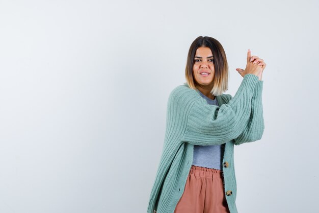 Ortrait de mujer mostrando gesto de pistola en ropa casual y mirando confiada vista frontal