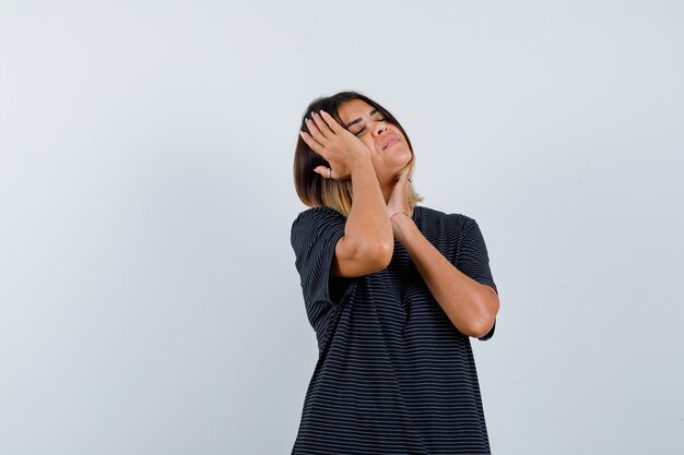 Ortrait de señorita tomados de la mano en la cabeza y la barbilla en vestido de polo y mirando fatigada vista frontal