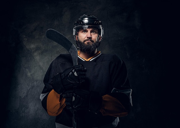 Foto gratuita en el oscuro estudio fotográfico, un brutal jugador de hockey experimentado tiene una sesión de fotos.