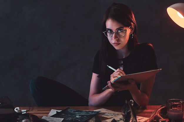 En el oscuro estudio lleno de luces de colores, la joven está trabajando en sus nuevas ideas creativas.