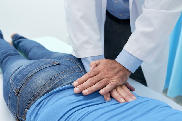 Osteópata recortada que ajusta la espalda del paciente con masaje