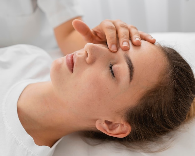 Osteópata tratando a una paciente masajeando su rostro de cerca