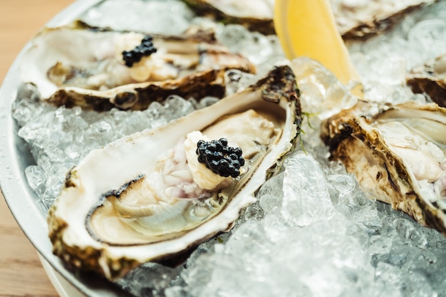 Ostras crudas y frescas con caviar encima y limón.