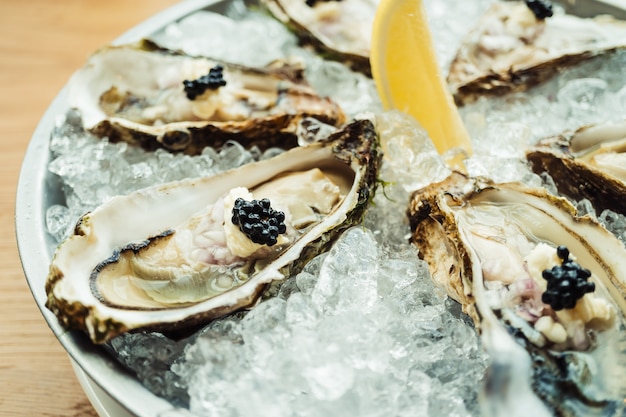 Ostras crudas y frescas con caviar encima y limón.