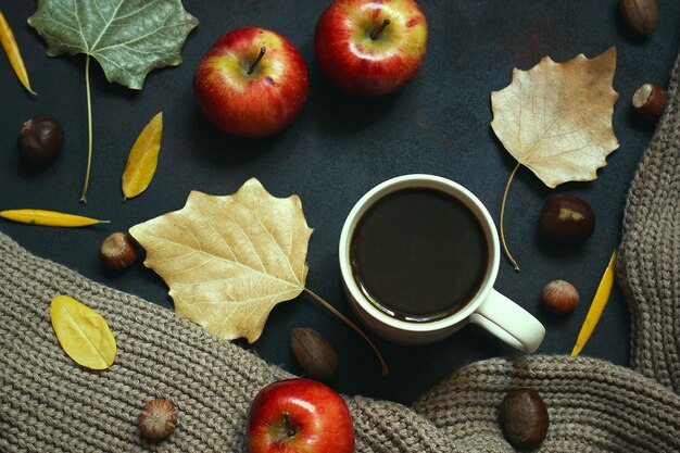 Otoño, hojas de otoño, una taza de café humeante y una bufanda o chaqueta cálida. Estacional, café de la mañana, domingo relajante y concepto de naturaleza muerta.