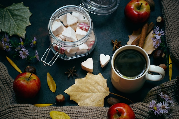 Otoño, hojas de otoño, una taza de café humeante y una bufanda o chaqueta cálida. Estacional, café de la mañana, domingo relajante y concepto de naturaleza muerta.