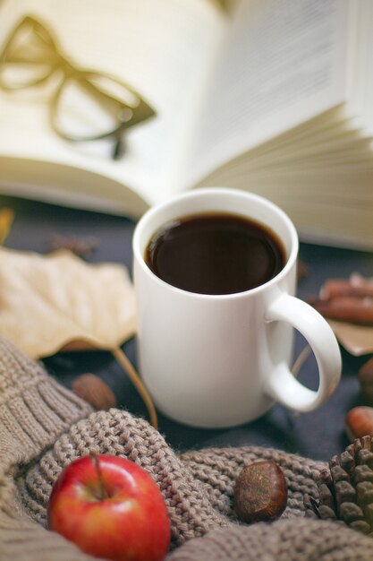 Otoño, hojas de otoño, una taza de café humeante y una bufanda o chaqueta cálida. Estacional, café de la mañana, domingo relajante y concepto de naturaleza muerta.