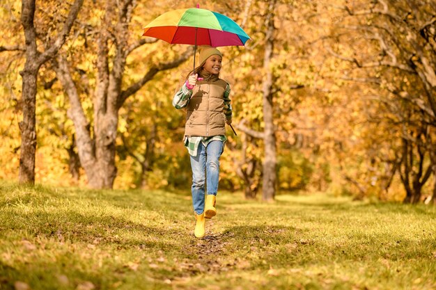 Otoño. Una niña con un paraguas brillante en un parque de otoño