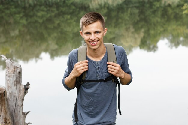 Oung boy sonriendo a la cámara cerca de un lago