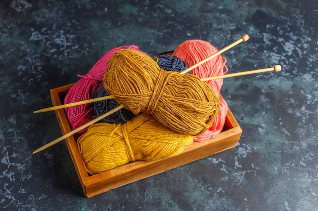 Foto gratuita ovillos de lana de diferentes colores con agujas de tejer.