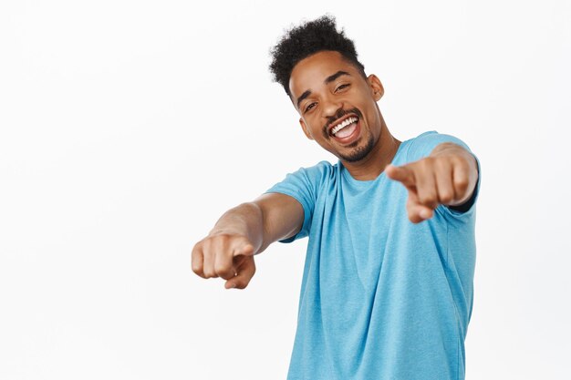 Oye, mi hombre. Chico afroamericano alegre señalando con el dedo a la cámara con cara feliz, felicitándote, elogiando el gran trabajo, eligiendo a la persona, de pie contra el fondo blanco