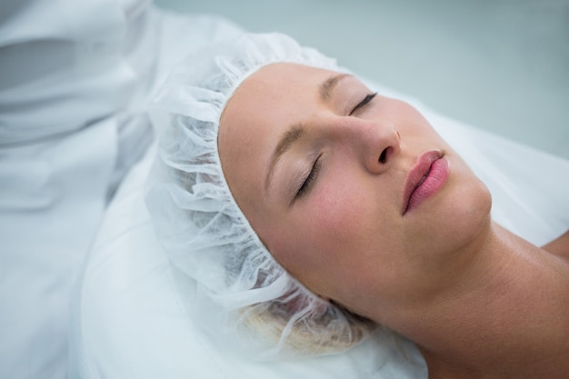 Paciente acostado en la cama mientras recibe tratamiento cosmético