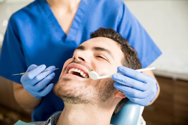 Paciente adulto medio que recibe tratamiento dental con herramientas de una dentista en la clínica