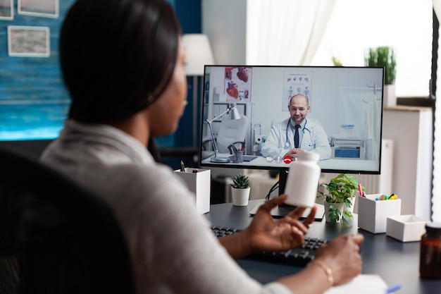 Foto gratuita paciente afroamericano discutiendo con el médico terapeuta durante la reunión de videollamada en línea