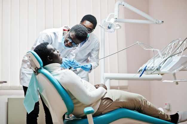 Paciente afroamericano en sillón dental Oficina de dentista y concepto de práctica médica Dentista profesional ayudando a su paciente en odontología médica Perforación de los dientes del paciente en la clínica