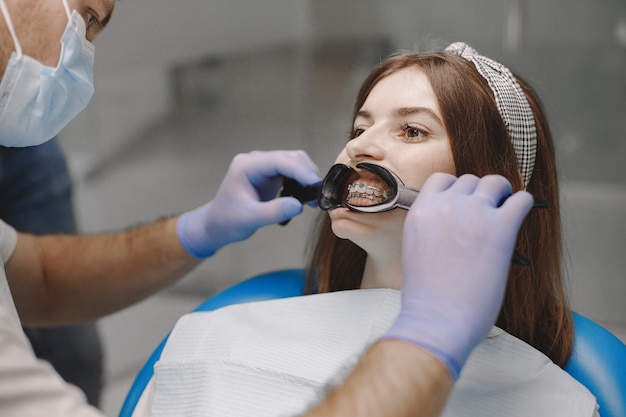 Paciente con brackets tiene un examen dental en el consultorio del dentista. Mujer vestida de blanco