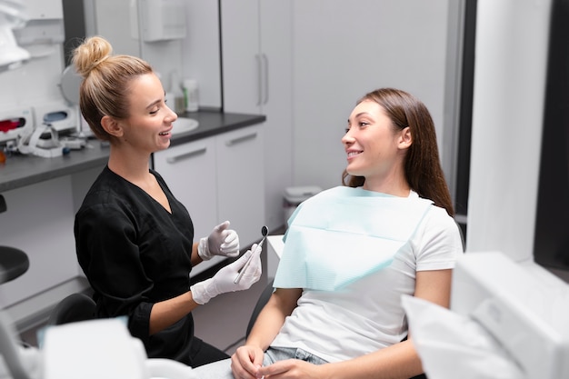 Paciente y dentista de tiro medio en la clínica