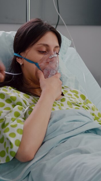 Paciente descansando en la cama con enfermedad respiratoria mientras los médicos monitorean el pulso cardíaco con oxímetro ...