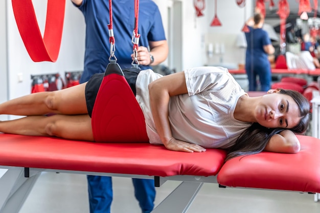 Foto gratuita paciente femenina colgando de suspensiones en el centro de rehabilitación