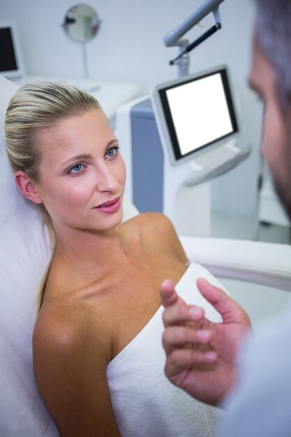 Paciente femenino acostado y mirando al médico