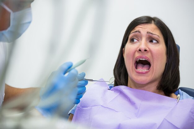 Paciente femenino asustado durante un chequeo dental
