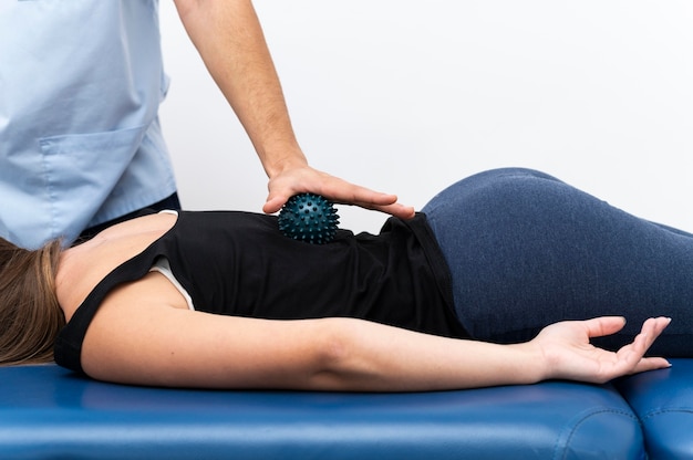 Paciente femenino recibiendo masaje de fisioterapeuta con bola