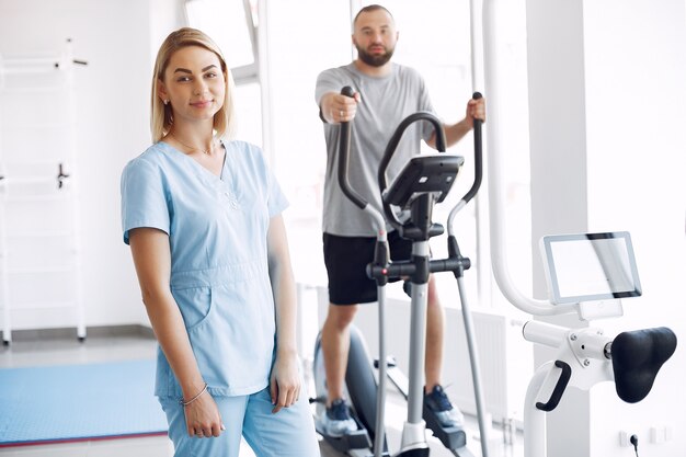 Paciente haciendo ejercicio en bicicleta de spinning en el gimnasio con el terapeuta