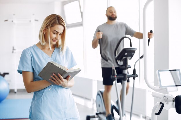 Paciente haciendo ejercicio en bicicleta de spinning en el gimnasio con el terapeuta