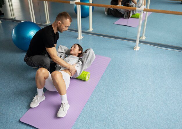 Paciente haciendo rehabilitación física ayudado por terapeutas