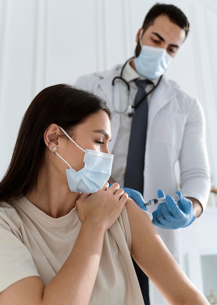 Foto gratuita paciente joven con máscara médica siendo vacunado por médico