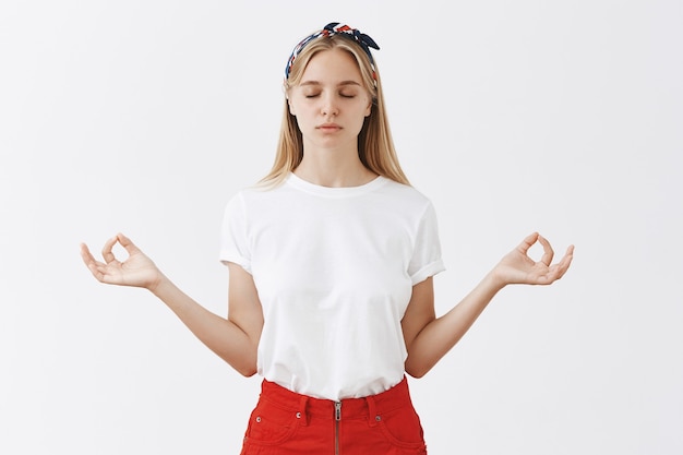 Paciente joven rubia posando contra la pared blanca