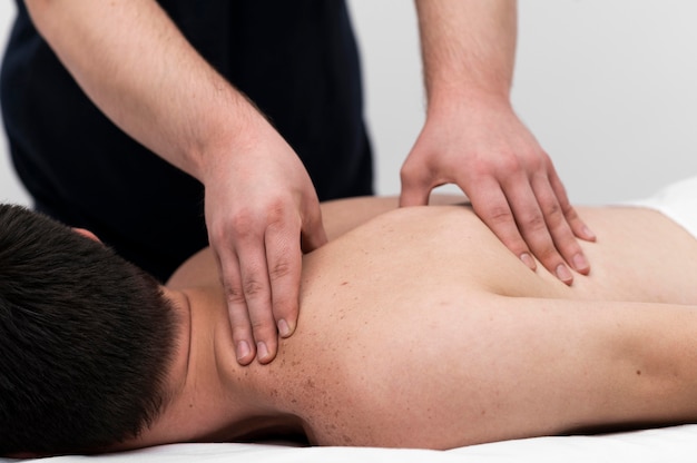 Paciente masculino recibiendo un masaje de espalda por fisioterapeuta