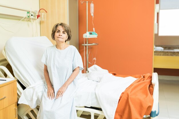 Paciente mayor con uniforme sentado en la cama en el hospital