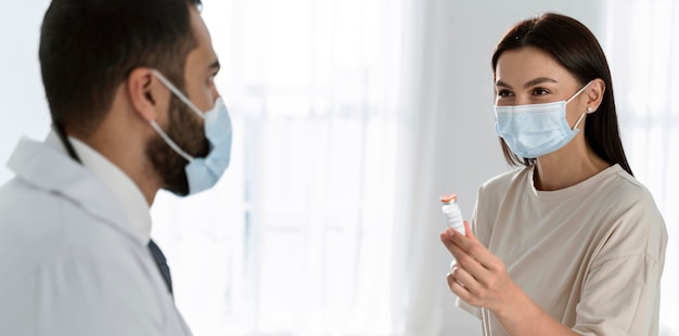 Paciente y médico hablando mientras usa máscaras médicas
